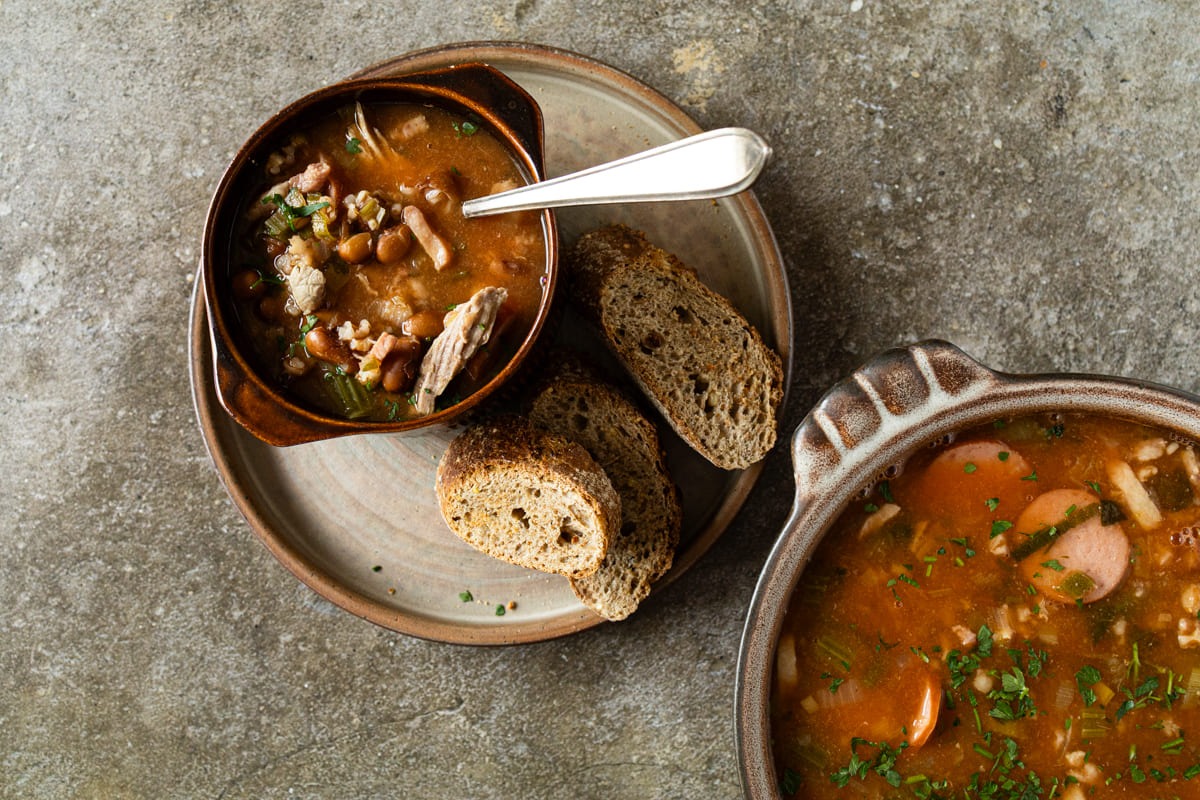 bruine bonensoep met spek en rookworst, geserveerd met roggebrood.