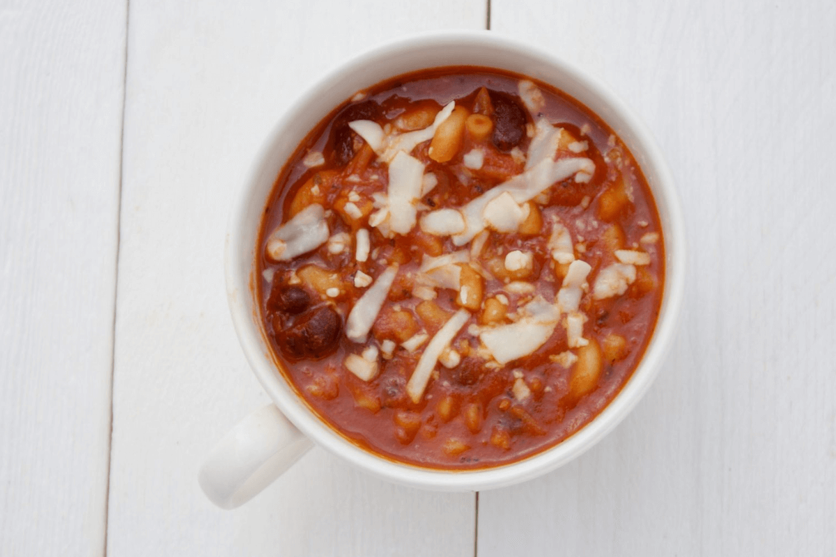 Close-up van een kom rode bonensoep, gegarneerd met geraspte kaas.