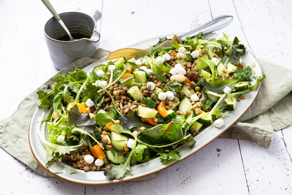grote schaal met verfrissende linzensalade met geitenkaas, komkommer en partjes sinaasappel.