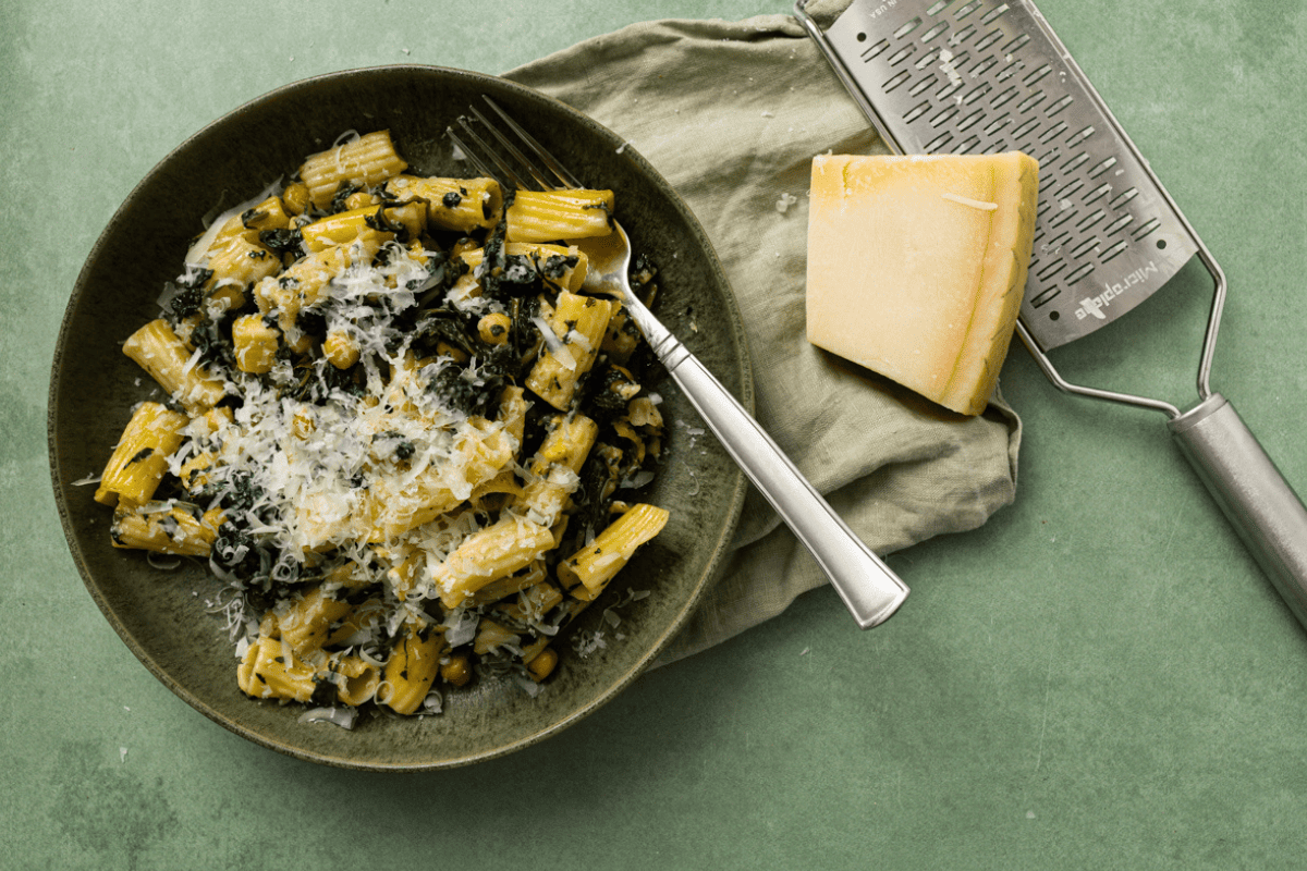 bord met rigtoni pasta met kikkererwten en spinazie, bestrooid met versgeraspte Parmezaanse kaas.